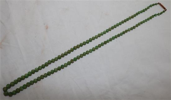 A Chinese carved jadeite bead necklace, early 20th century, total length 72.5cm, largest bead 9mm